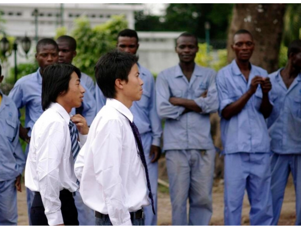 Les représentants de la China Railways Engineering Company (CREC) passent devant des ouvriers congolais, à Kinshasa, en mars 2010. REUTERS/Katrina Manson