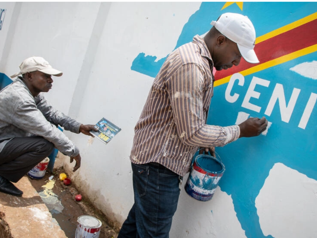 Des hommes peignent le logo de la Ceni (illustration). Caroline Thirion / AFP